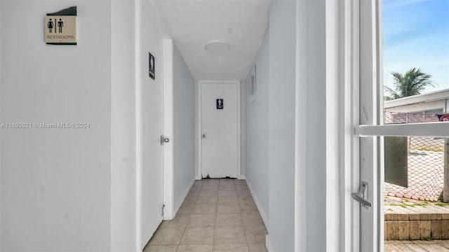 hall featuring light tile patterned floors and baseboards