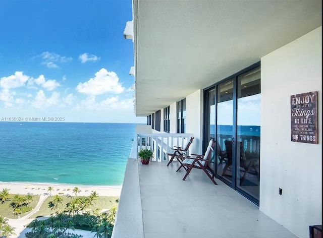 balcony featuring a beach view and a water view