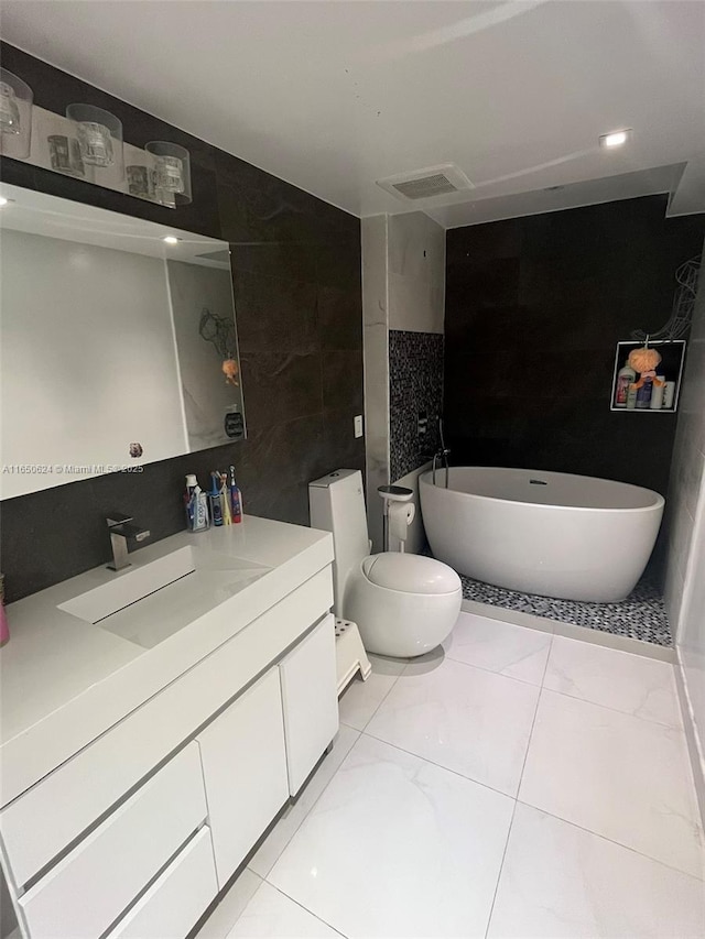 bathroom featuring vanity, tile patterned floors, a washtub, toilet, and tile walls