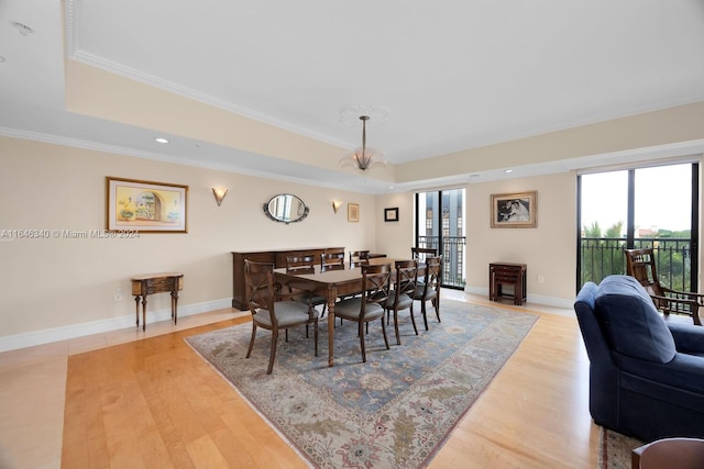 dining space featuring ornamental molding, a chandelier, and light hardwood / wood-style floors