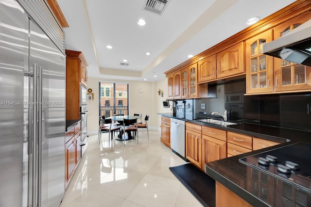 kitchen with built in appliances, light tile patterned floors, sink, decorative backsplash, and extractor fan