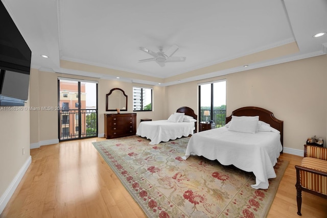 bedroom with light hardwood / wood-style floors, a tray ceiling, access to exterior, ceiling fan, and ornamental molding