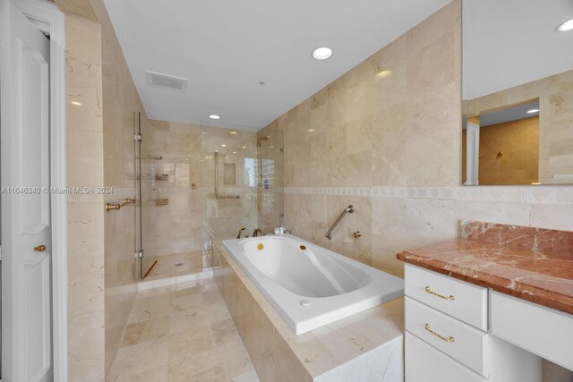 bathroom with vanity, independent shower and bath, and tile walls