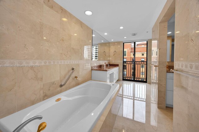 bathroom featuring tile walls, tiled tub, and vanity