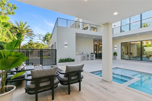 exterior space with an outdoor hangout area, an in ground hot tub, and a balcony