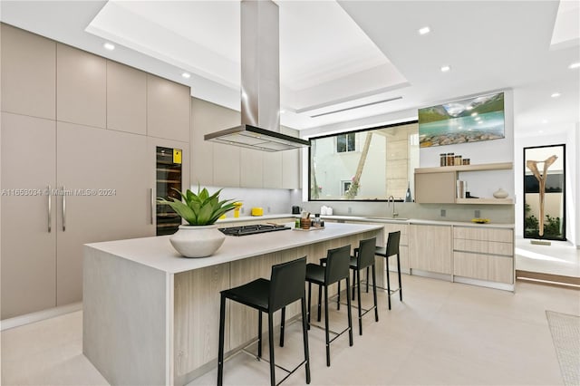 kitchen featuring a kitchen breakfast bar, stainless steel gas stovetop, sink, light brown cabinets, and a large island