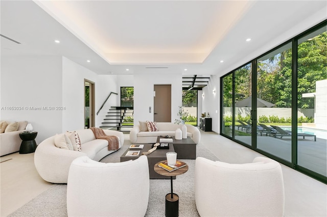 living room with a wall of windows, a tray ceiling, and carpet floors