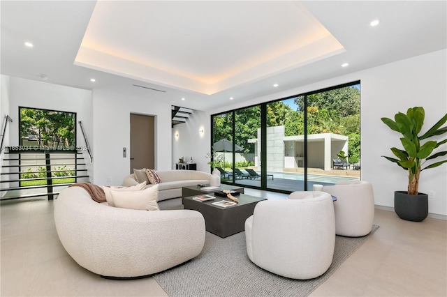 living room featuring a tray ceiling and a healthy amount of sunlight