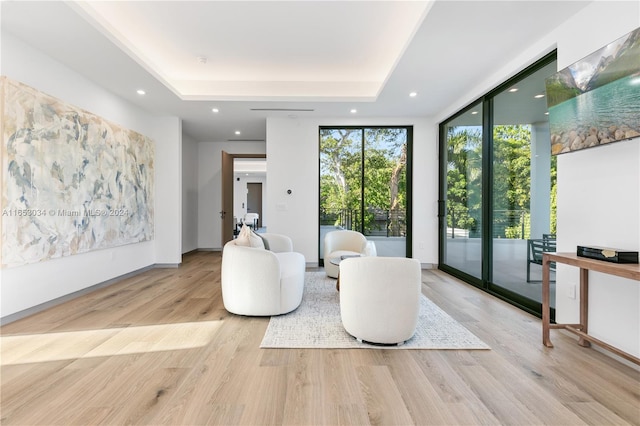 interior space with light wood-type flooring, floor to ceiling windows, and a raised ceiling