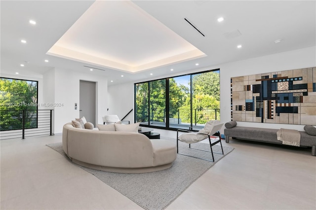 living room featuring plenty of natural light, floor to ceiling windows, and a tray ceiling