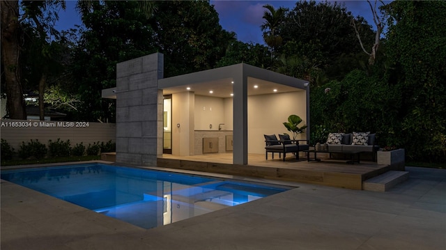 pool at twilight with a patio and outdoor lounge area