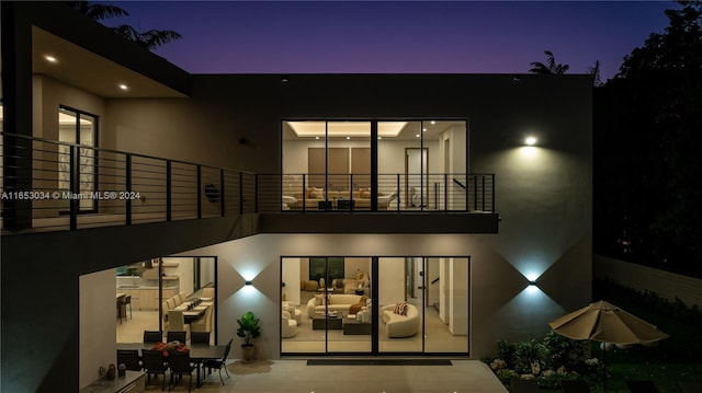 back house at dusk with a balcony