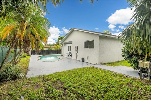 back of property featuring a fenced in pool, a lawn, and a patio