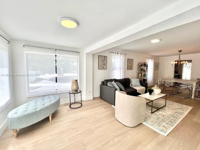 living room with an inviting chandelier, light hardwood / wood-style floors, and a healthy amount of sunlight