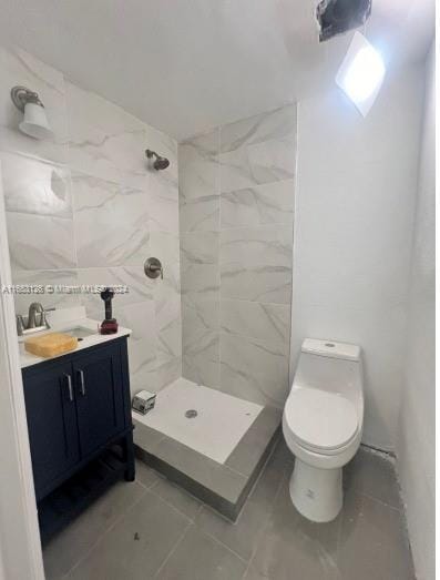 bathroom with tasteful backsplash, vanity, a tile shower, toilet, and tile patterned floors