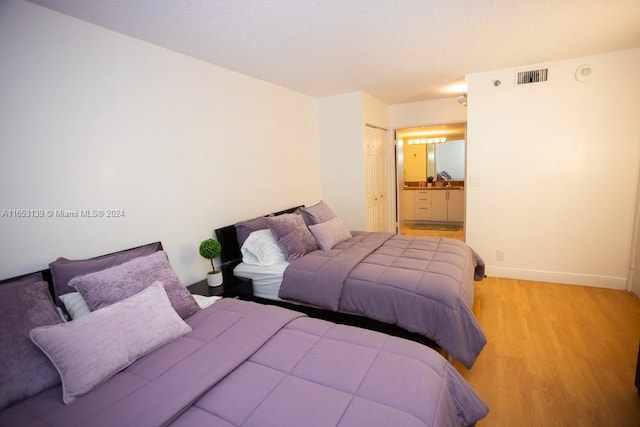 bedroom with light wood-type flooring and connected bathroom