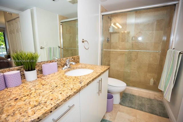 bathroom with tile patterned floors, vanity, toilet, and a shower with shower door