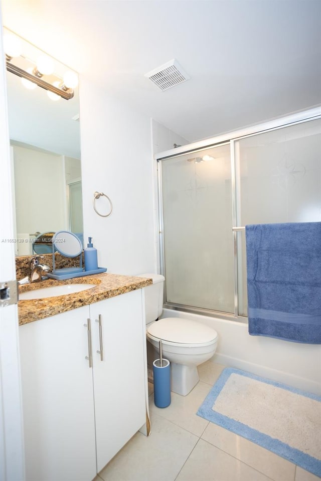 full bathroom with shower / bath combination with glass door, vanity, tile patterned floors, and toilet