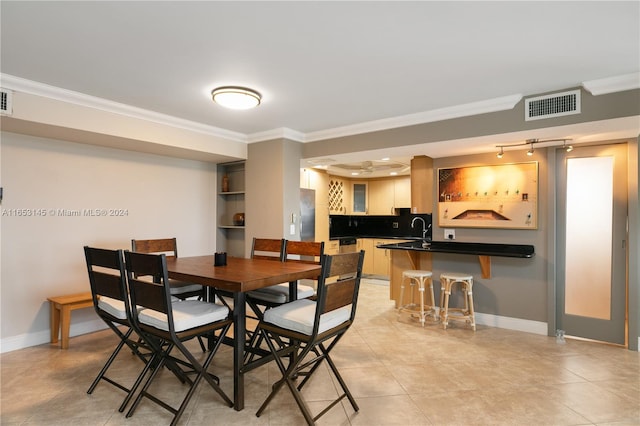 dining area featuring ornamental molding, sink, and light tile patterned floors