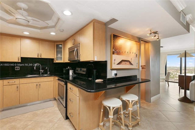 kitchen with light brown cabinetry, stainless steel appliances, sink, and kitchen peninsula