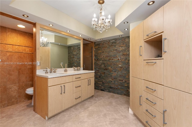 bathroom with a raised ceiling, vanity, tile patterned flooring, toilet, and a chandelier