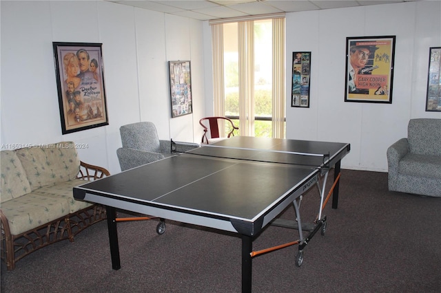 recreation room with dark carpet and a paneled ceiling