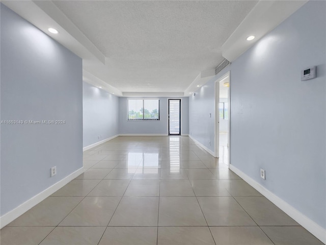 spare room featuring a textured ceiling and light tile patterned flooring