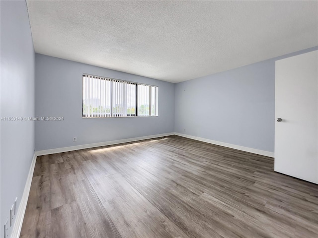 empty room with a textured ceiling and hardwood / wood-style floors