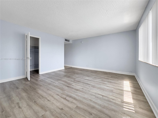 unfurnished bedroom featuring a textured ceiling, light hardwood / wood-style floors, and a closet