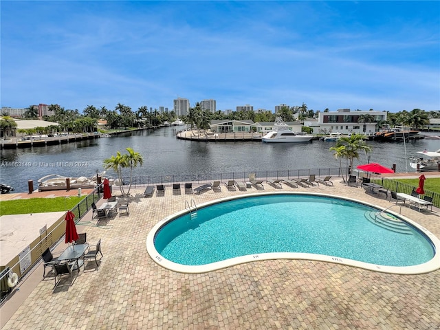 view of swimming pool featuring a patio and a water view