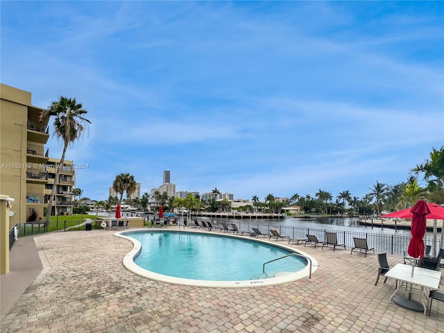 view of pool with a water view and a patio area