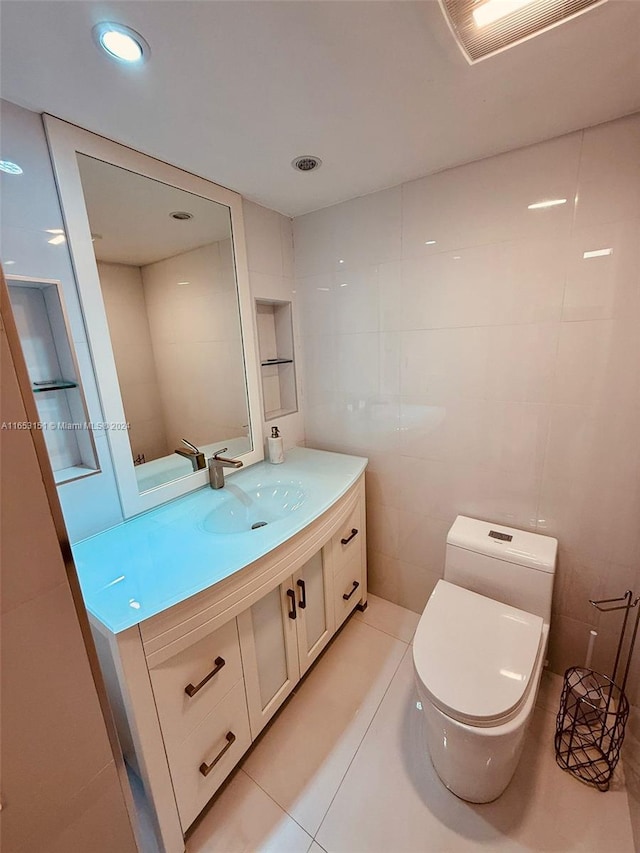 bathroom featuring toilet, vanity, tile walls, and tile patterned flooring