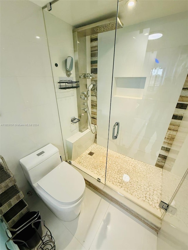 bathroom with tile patterned flooring, toilet, and a shower with door