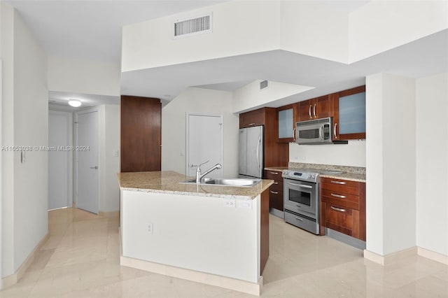 kitchen with stainless steel appliances, visible vents, glass insert cabinets, a sink, and light stone countertops