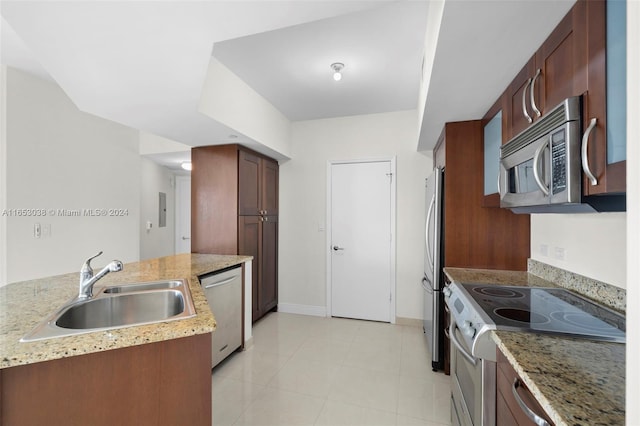 kitchen with light stone countertops, baseboards, appliances with stainless steel finishes, and a sink