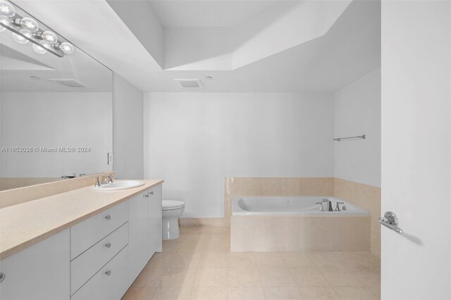 bathroom with vanity, toilet, and tiled bath