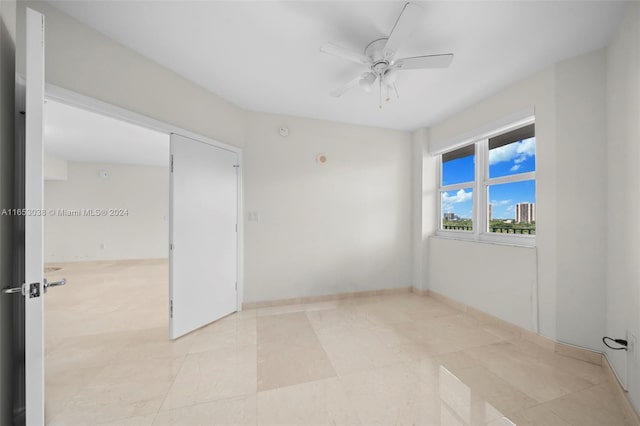 spare room featuring a ceiling fan and baseboards