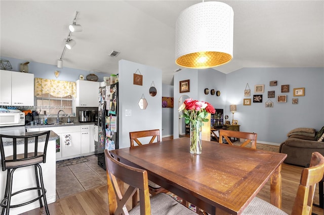 dining room featuring dark wood-type flooring, vaulted ceiling, sink, and track lighting