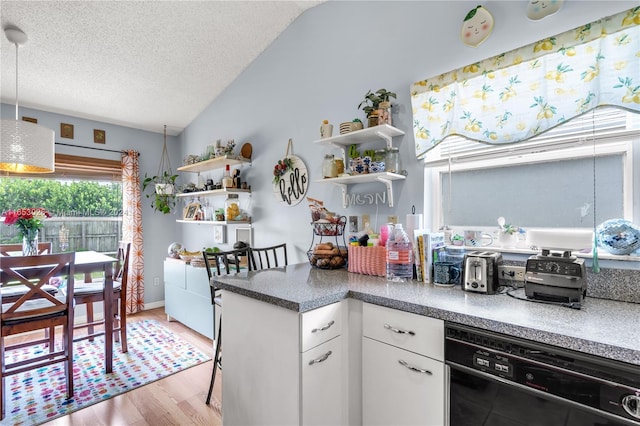 kitchen with white cabinets, light hardwood / wood-style flooring, vaulted ceiling, black dishwasher, and a textured ceiling