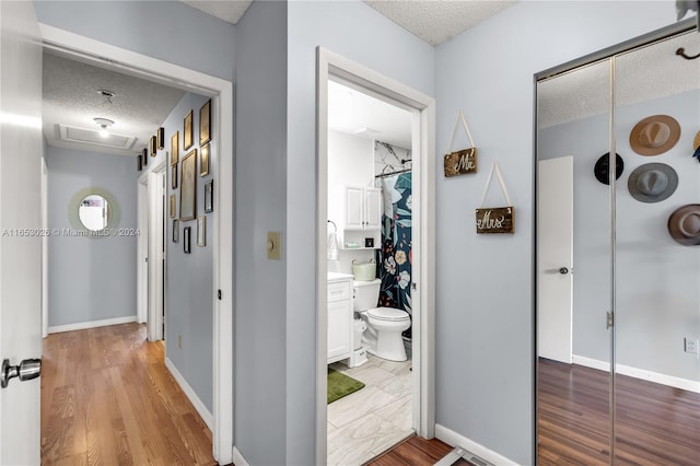 corridor with hardwood / wood-style floors and a textured ceiling