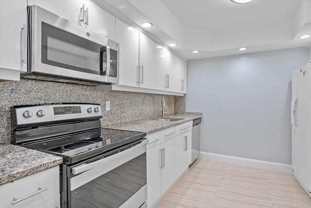 kitchen featuring backsplash, appliances with stainless steel finishes, sink, light stone counters, and white cabinets