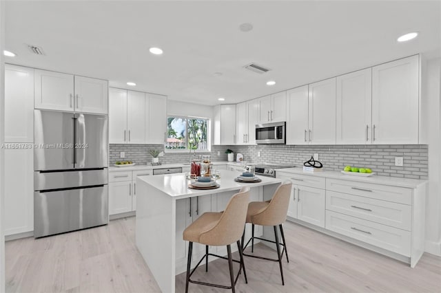 kitchen featuring white cabinets, a kitchen breakfast bar, light wood-type flooring, and stainless steel appliances