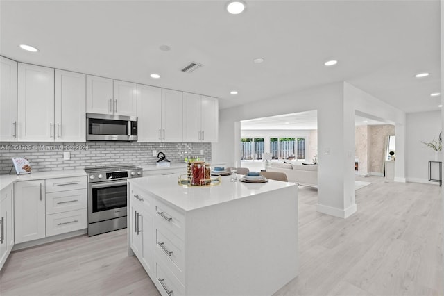 kitchen featuring white cabinets, a kitchen island, stainless steel appliances, and light hardwood / wood-style flooring