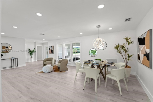 dining area with an inviting chandelier and light hardwood / wood-style flooring