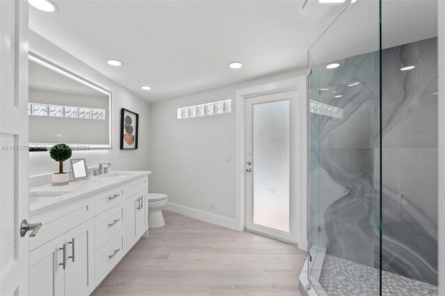 bathroom featuring hardwood / wood-style flooring, vanity, toilet, and a shower with door