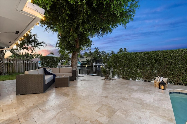 patio terrace at dusk with an outdoor living space and a water view