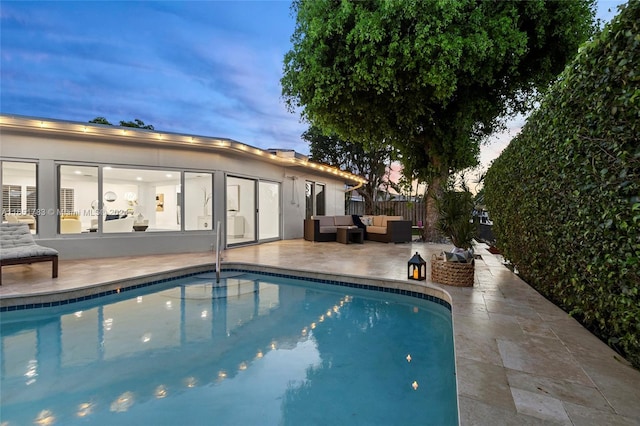 pool at dusk with a patio area and an outdoor hangout area