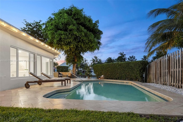 pool at dusk with a patio area