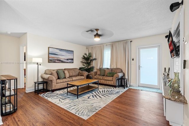 living room featuring a textured ceiling, ceiling fan, and dark hardwood / wood-style floors