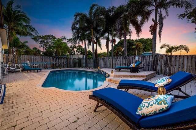 pool at dusk with a patio area